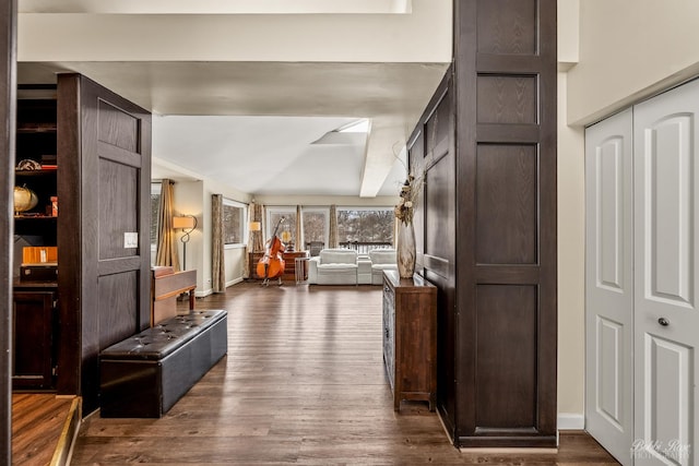 hall featuring lofted ceiling, dark wood finished floors, and baseboards