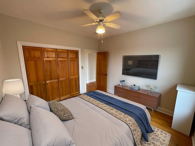 bedroom featuring a closet, baseboards, ceiling fan, and light wood finished floors