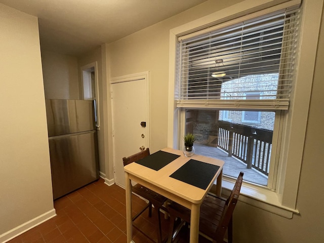 dining room featuring brick floor and baseboards