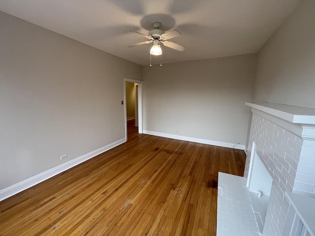 unfurnished living room featuring baseboards, wood-type flooring, and ceiling fan