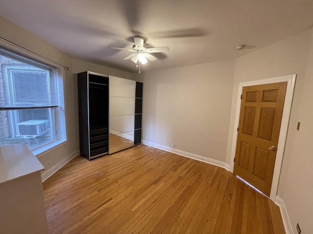 unfurnished bedroom featuring cooling unit, baseboards, light wood-style floors, and a ceiling fan