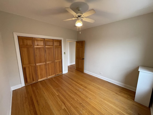 unfurnished bedroom featuring light wood-type flooring, baseboards, a closet, and a ceiling fan