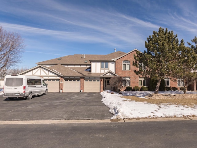 townhome / multi-family property with a garage, aphalt driveway, and brick siding