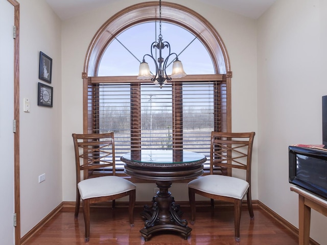 dining area with a healthy amount of sunlight, dark wood finished floors, and a notable chandelier