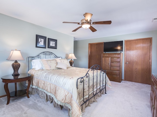 bedroom with visible vents, two closets, a ceiling fan, and light colored carpet