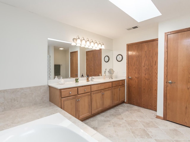 bathroom featuring a skylight, a sink, visible vents, double vanity, and a bathtub