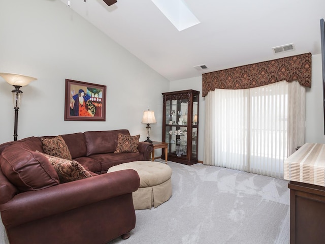 carpeted living area with a ceiling fan, a skylight, visible vents, and high vaulted ceiling