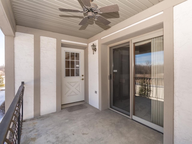 doorway to property with a balcony, ceiling fan, and stucco siding