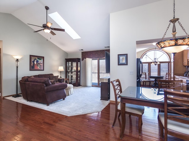 dining space featuring a skylight, dark wood finished floors, visible vents, high vaulted ceiling, and ceiling fan with notable chandelier