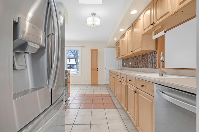 kitchen with appliances with stainless steel finishes, light countertops, a sink, and light brown cabinets