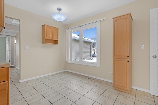 unfurnished room with light tile patterned flooring, visible vents, and baseboards