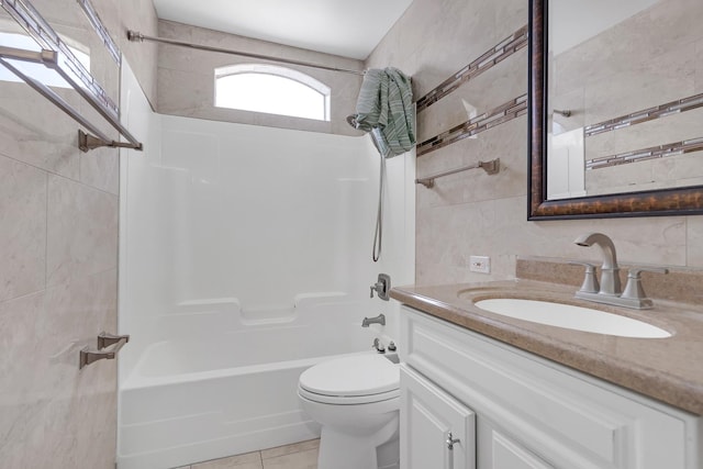 full bathroom featuring bathing tub / shower combination, toilet, tile patterned floors, vanity, and tile walls