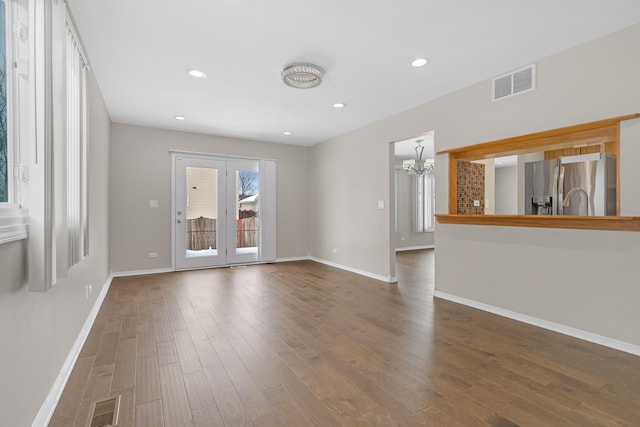 unfurnished room featuring dark wood-type flooring, visible vents, and baseboards