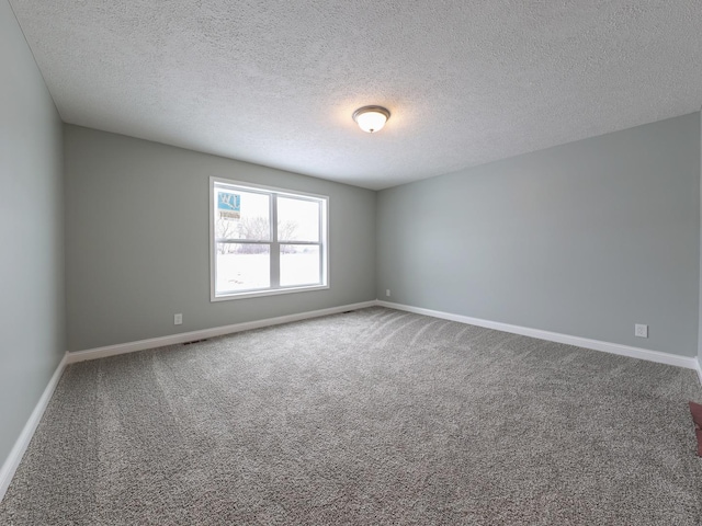 unfurnished room with a textured ceiling, carpet flooring, and baseboards