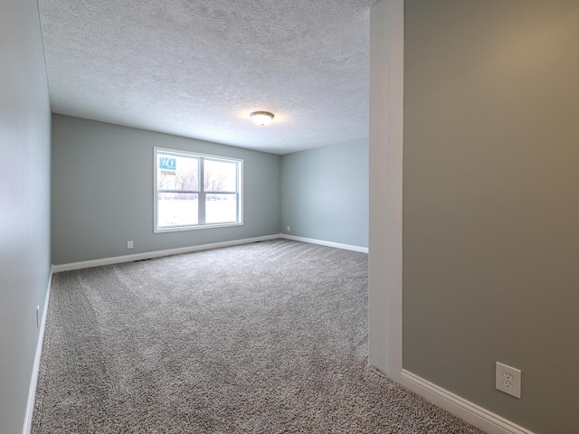 carpeted empty room featuring a textured ceiling and baseboards