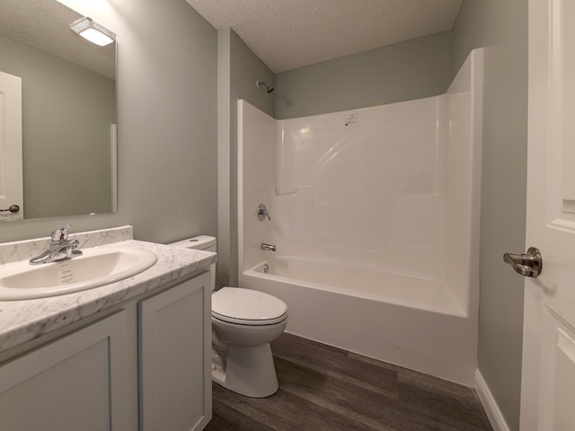 full bath with toilet, washtub / shower combination, a textured ceiling, vanity, and wood finished floors