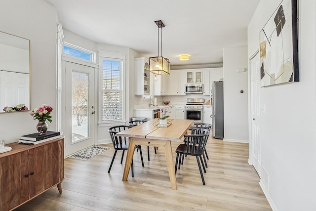 dining area featuring light wood finished floors and baseboards