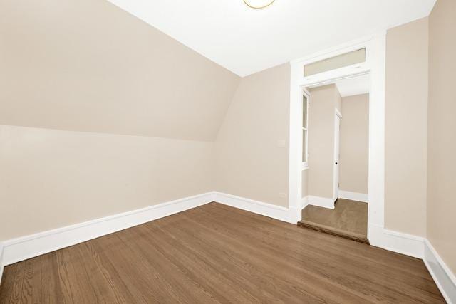 additional living space with lofted ceiling, baseboards, and dark wood-style flooring