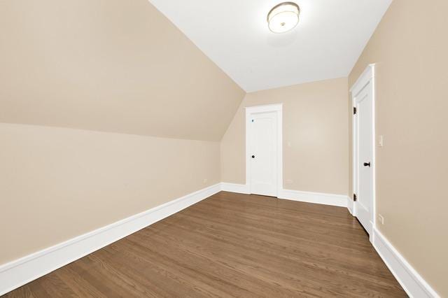 additional living space with dark wood-style floors, baseboards, and vaulted ceiling