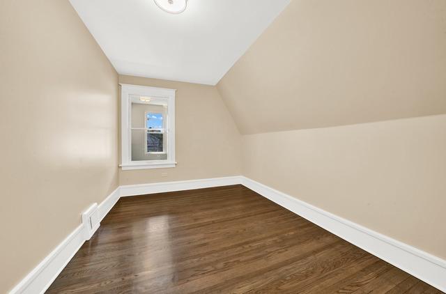 additional living space with dark wood-type flooring, vaulted ceiling, and baseboards