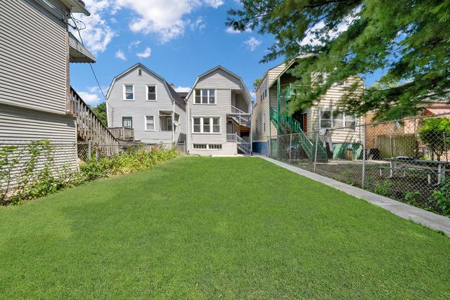 back of house featuring a lawn, a gambrel roof, and fence