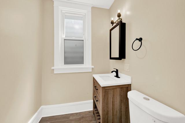 bathroom with toilet, baseboards, and vanity