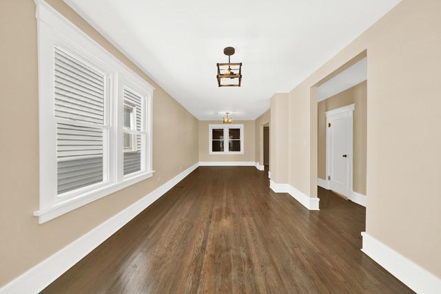 hallway with dark wood-style floors, a chandelier, and baseboards