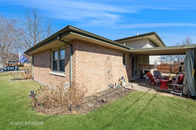 view of side of property with brick siding, fence, a lawn, and a patio