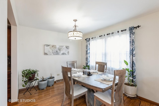 dining room featuring wood finished floors, visible vents, and baseboards