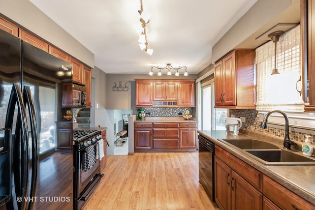 kitchen featuring brown cabinets, black appliances, light wood finished floors, and a sink