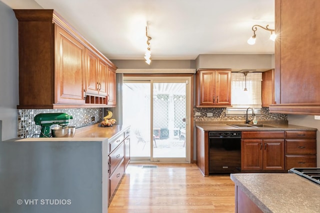 kitchen with a sink, visible vents, light wood-style floors, black dishwasher, and backsplash