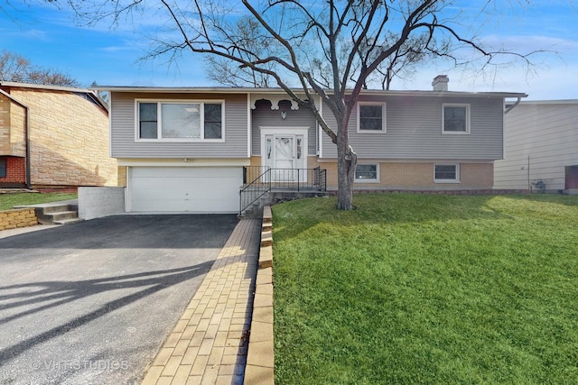 split foyer home with a chimney, a front lawn, a garage, aphalt driveway, and brick siding