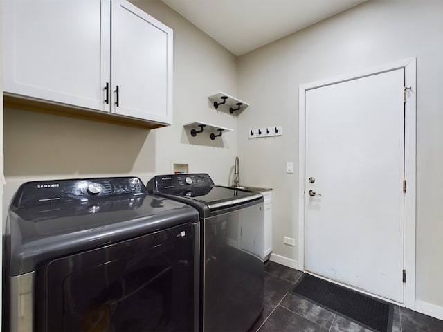 laundry area featuring cabinet space, baseboards, dark tile patterned floors, washing machine and dryer, and a sink