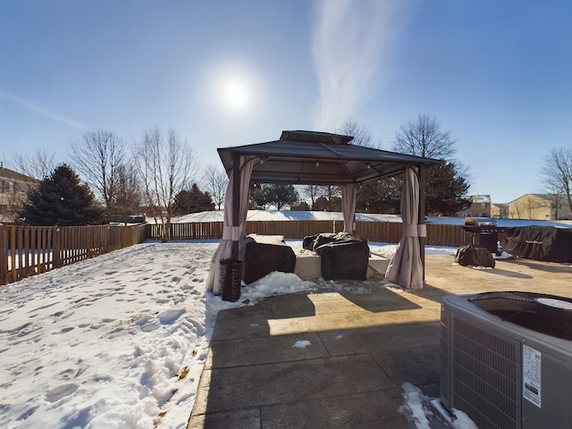 snow covered patio with a gazebo, central AC unit, and a fenced backyard