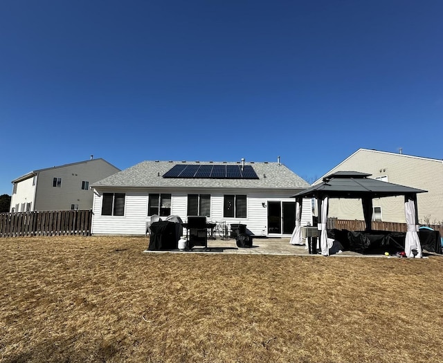 back of property with a patio, solar panels, a lawn, a gazebo, and fence