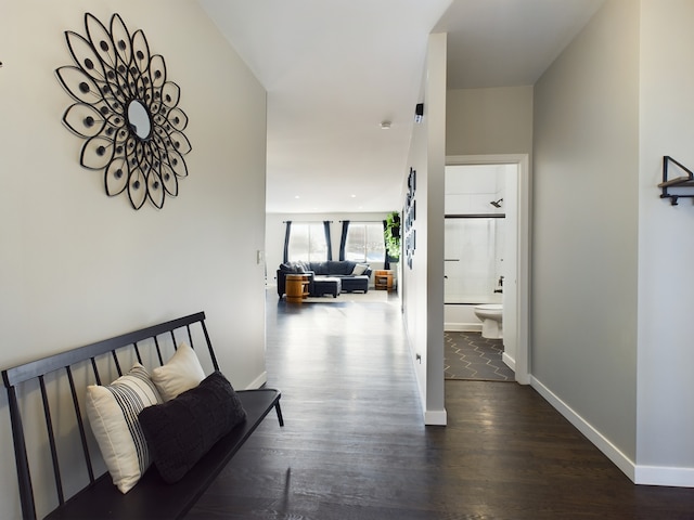 corridor featuring baseboards and wood finished floors