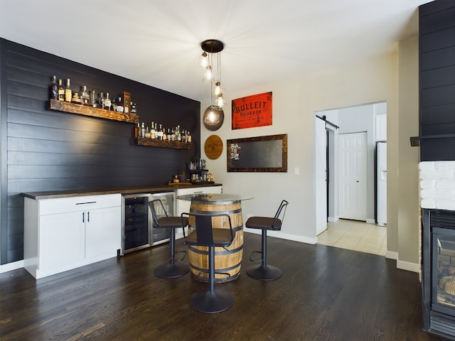 bar featuring a bar, light wood-type flooring, a barn door, and wine cooler