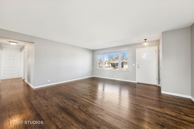 unfurnished living room with dark wood-type flooring and baseboards