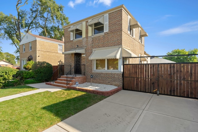 view of front of property with brick siding, a front yard, fence, and a gate