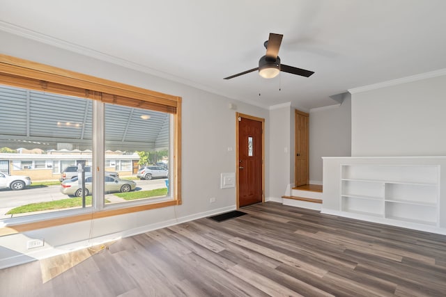 unfurnished living room with visible vents, ornamental molding, a ceiling fan, wood finished floors, and baseboards