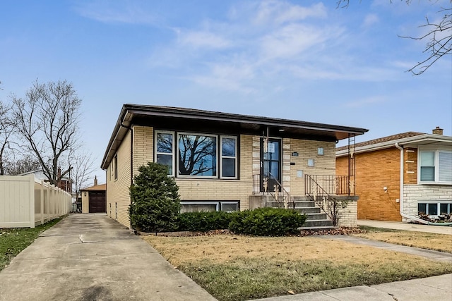 view of front facade with an outbuilding, brick siding, fence, and a detached garage