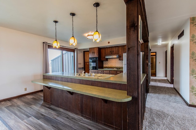 kitchen with a peninsula, under cabinet range hood, and a breakfast bar area