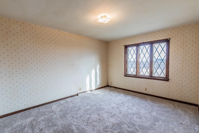 carpeted spare room featuring baseboards, a baseboard radiator, and wallpapered walls