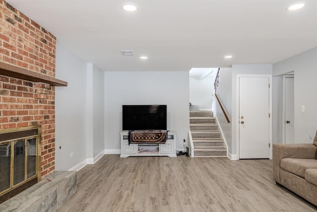 unfurnished living room with visible vents, stairway, light wood-type flooring, a brick fireplace, and recessed lighting