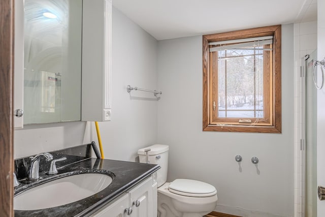 bathroom with toilet, an enclosed shower, and vanity