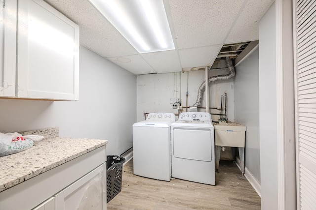 laundry area with a sink, cabinet space, light wood-style flooring, and washer and dryer