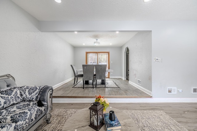 dining room featuring arched walkways, light wood-type flooring, visible vents, and baseboards