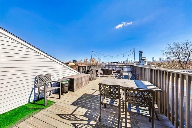 wooden deck featuring outdoor dining area and a city view