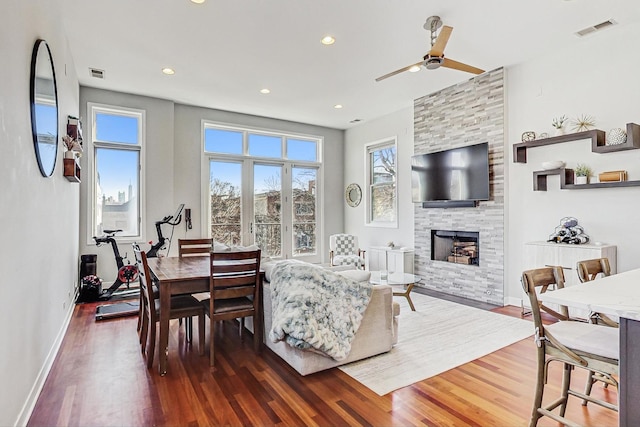 dining space featuring dark wood finished floors, visible vents, a stone fireplace, and baseboards