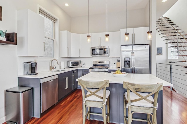 kitchen featuring a toaster, dark wood-style flooring, a sink, appliances with stainless steel finishes, and a kitchen bar